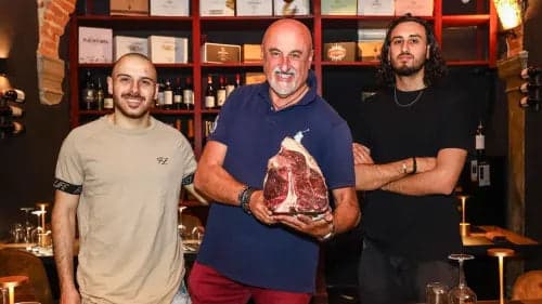 Lo staff della Casa della Bistecca con una costata, davanti alla cantina