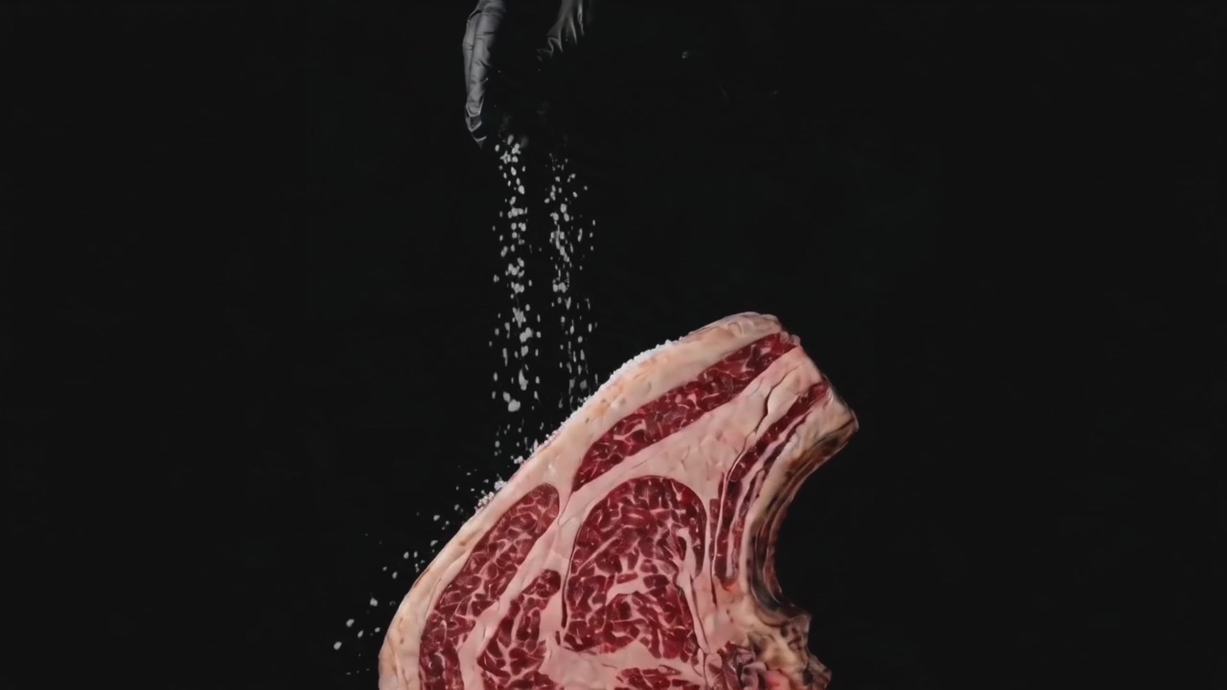 Una costata frollata salata a mano, su fondo nero