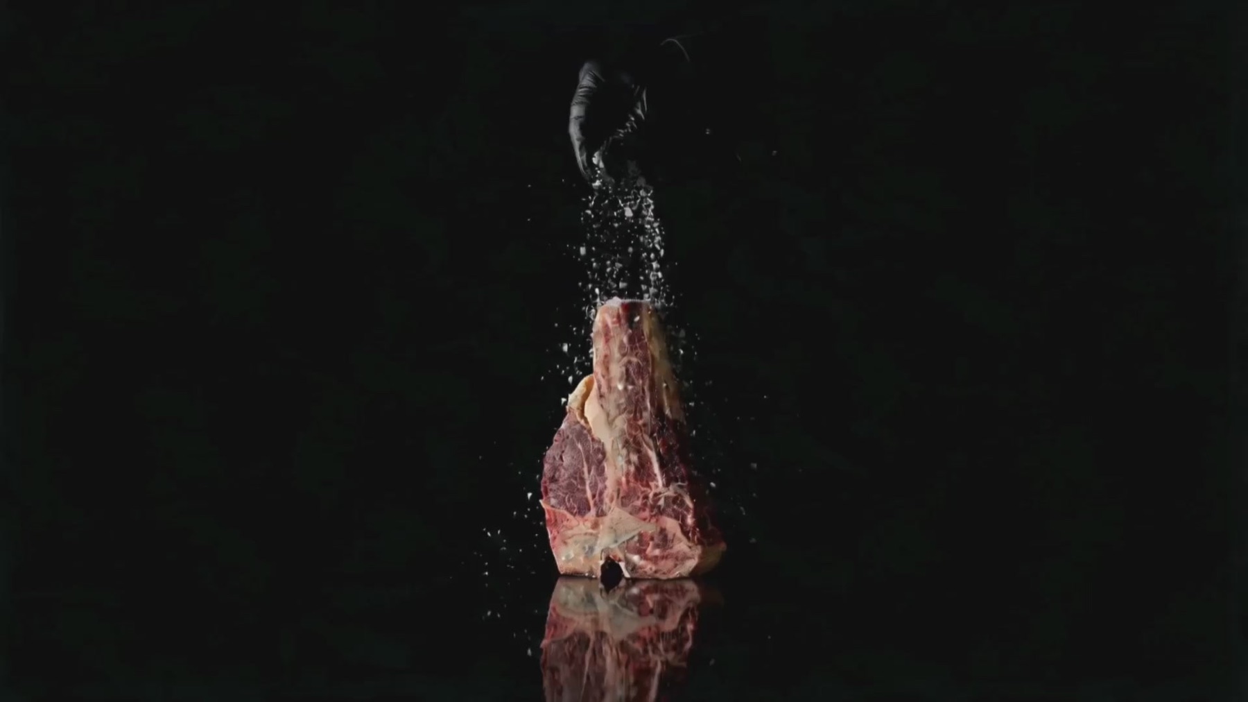 Una T-bone in piedi, salata, su fondo nero